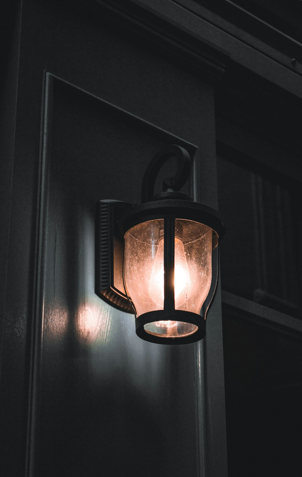 black framed clear glass lamp sconce turned on