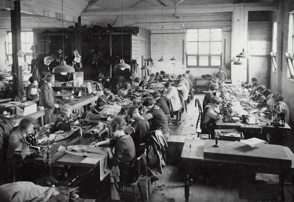 a black-and-white photo of workers sewing garments in a factory