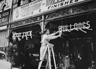 Technicians installing a monument sign at ground level outside a retail store.