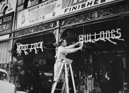 Technicians installing a monument sign at ground level outside a retail store.