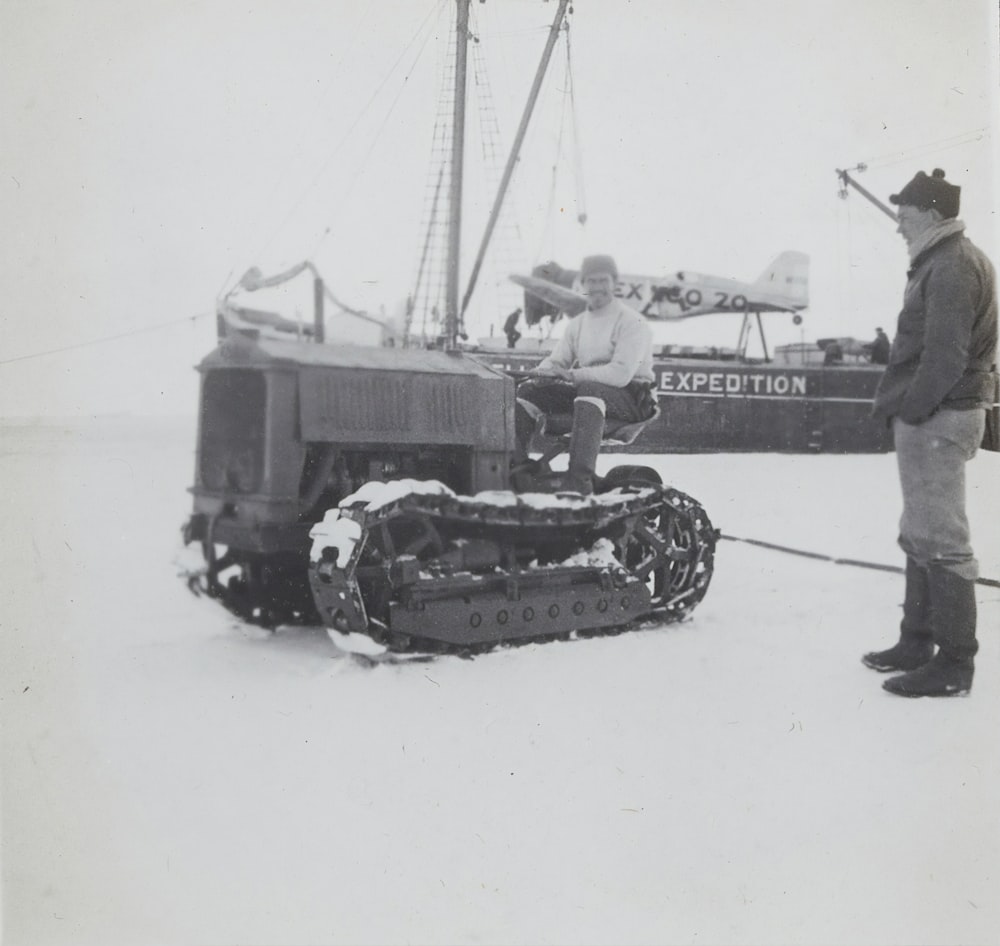 grayscale photography of man standing near a tractor