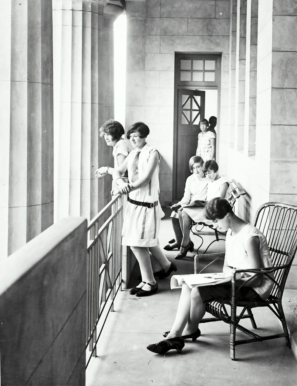 gruppo di donna che si siede e si leva in piedi accanto alla ringhiera