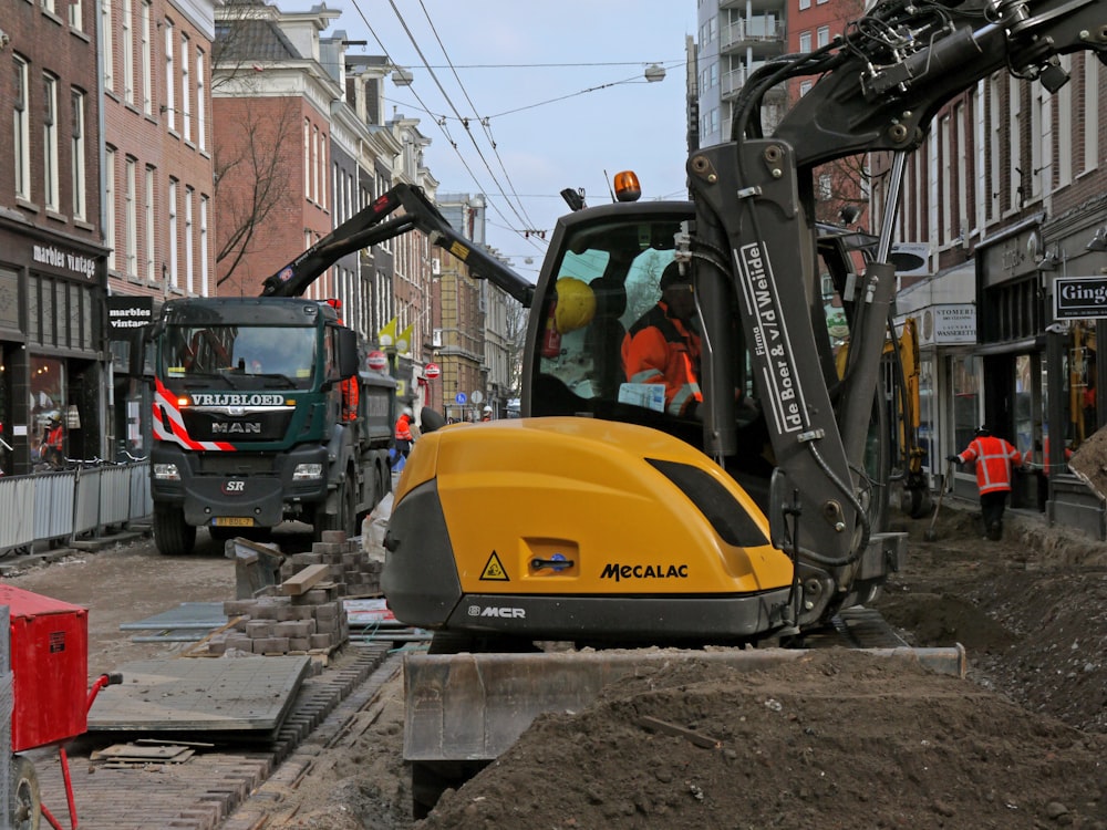 person using heavy equipment near vehicles, people, and buildings