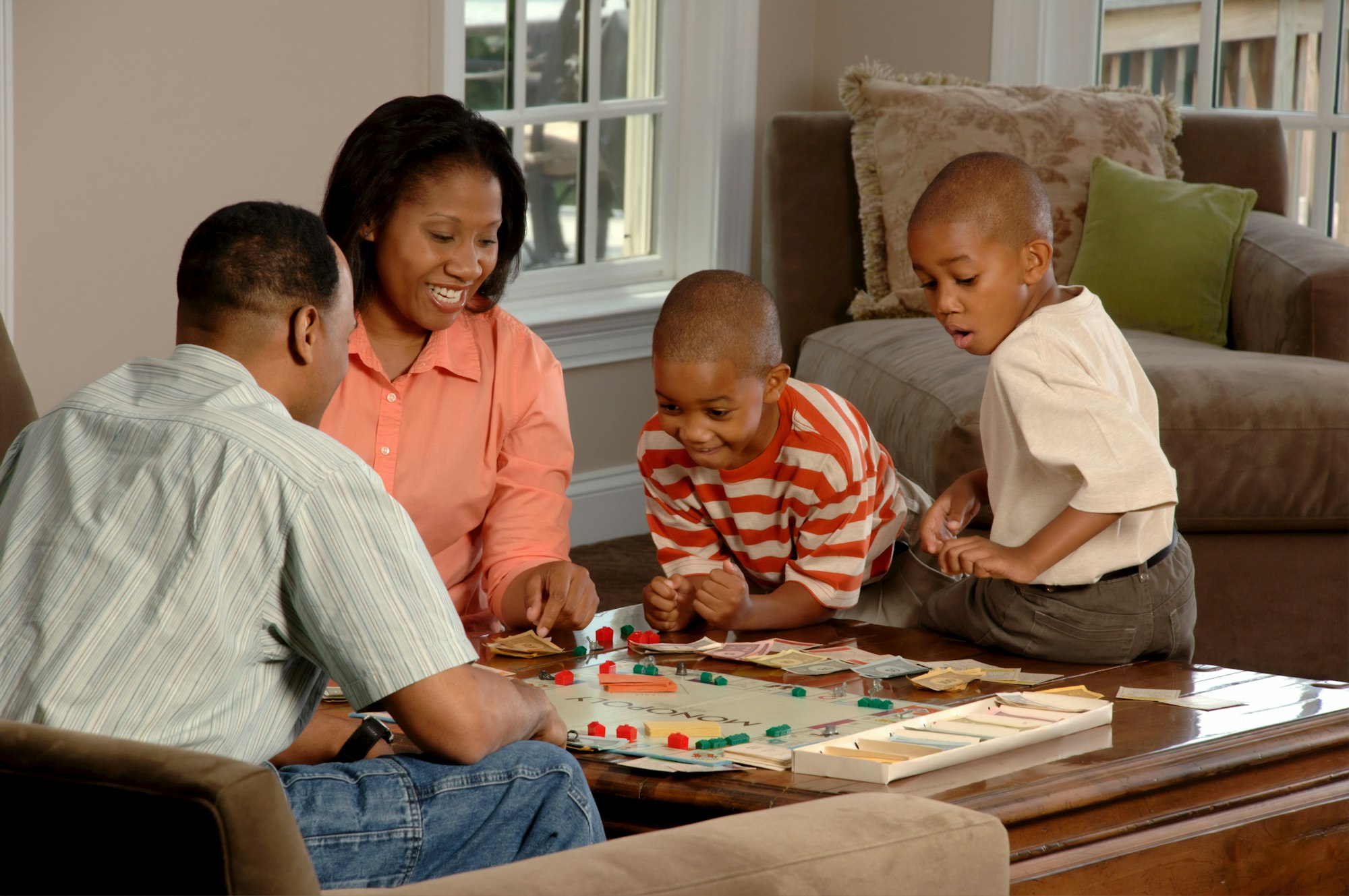 Family Playing Board Game. An African-American family (adult male and female and two male children) sit around a coffee table playing a board game.  Photographer Bill Branson 