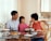 A smiling family sitting together at a kitchen table, discussing health insurance options.