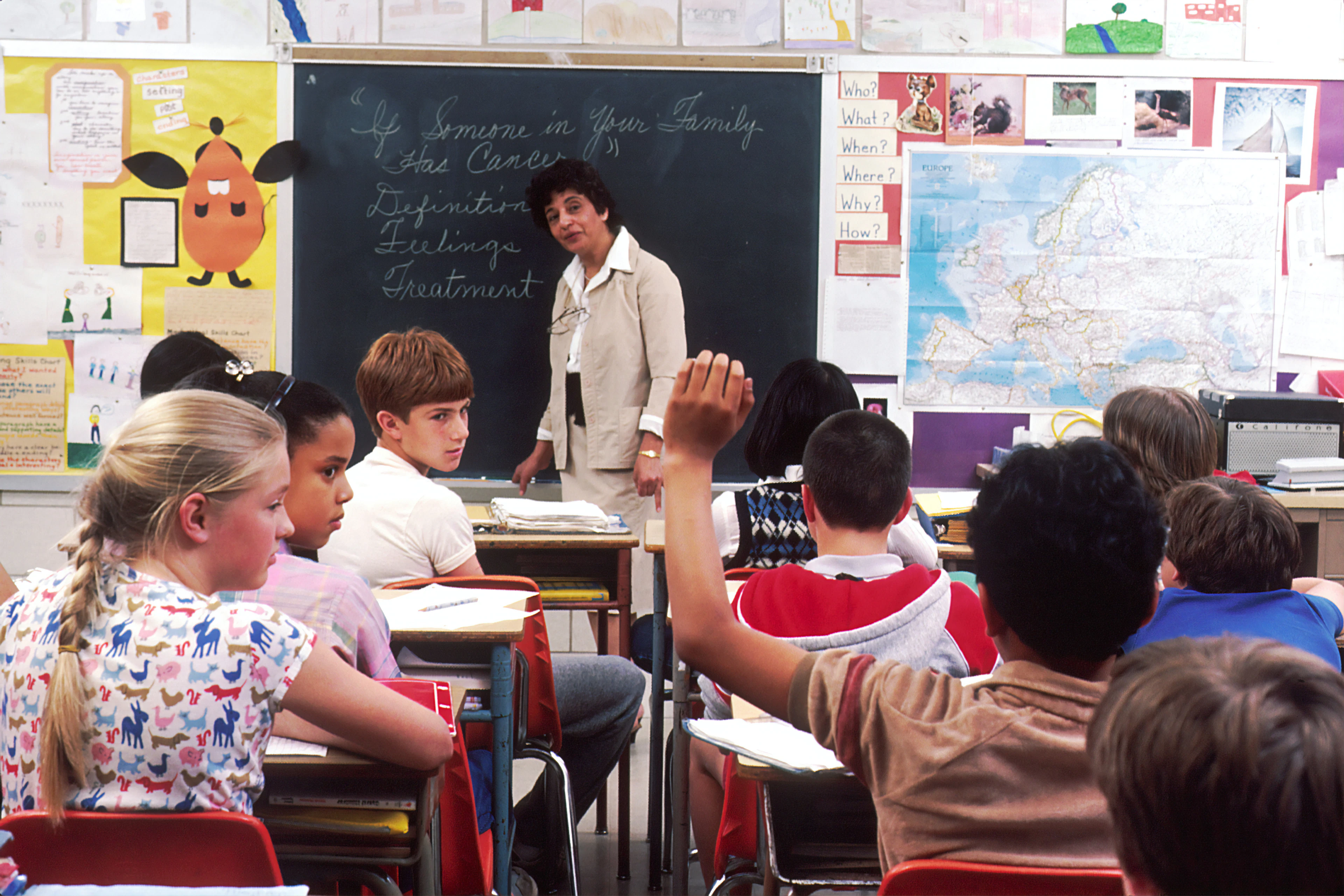 A teacher guiding young students at the chalkboard