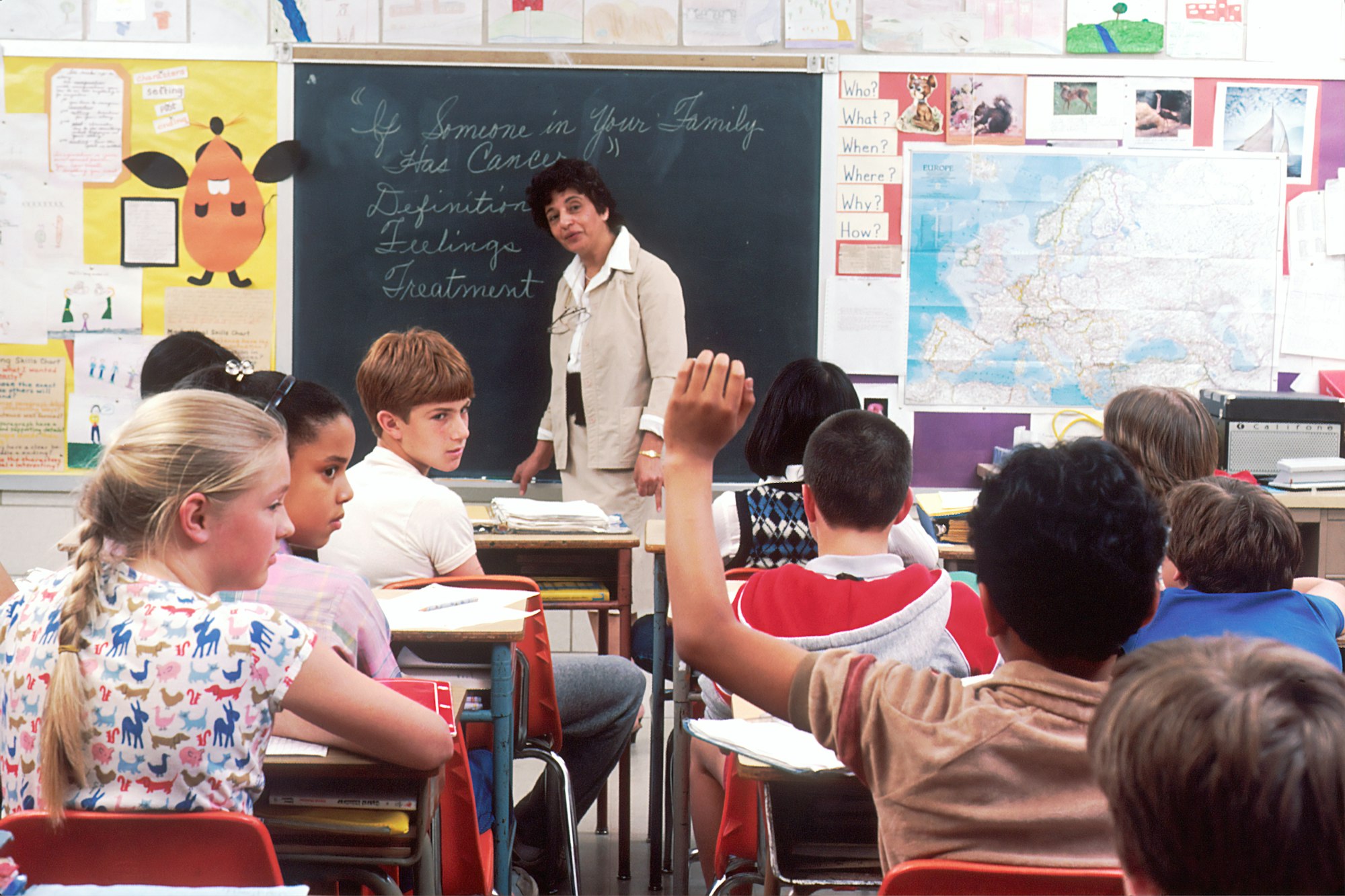 Children in a Classroom. In the back of a classroom, are children about 11 years old with a female teacher talking about the subject - If Someone in Your Family Has Cancer. Photographer Michael Anderson