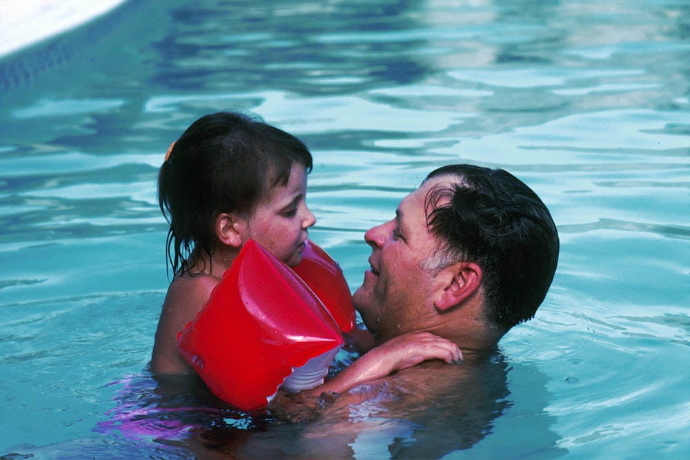 man with toddler girl in swimming pool