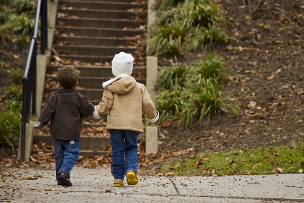 two toddlers walking towards stairs