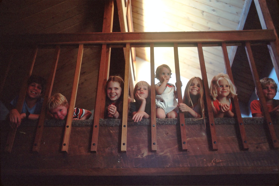 Children Sitting on a Staircase. Seven children peeking through a bannister railing on a staircase. They are members of a Mormon family who are presently being studied for their low cancer death rate. Pediatric, childhood, AYA. Photographer Linda Bartlett