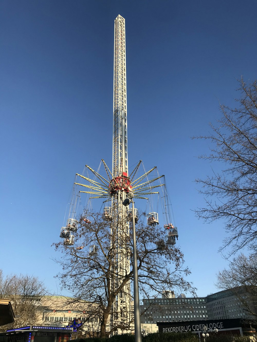 amusement park tower ride near trees and buildings during day