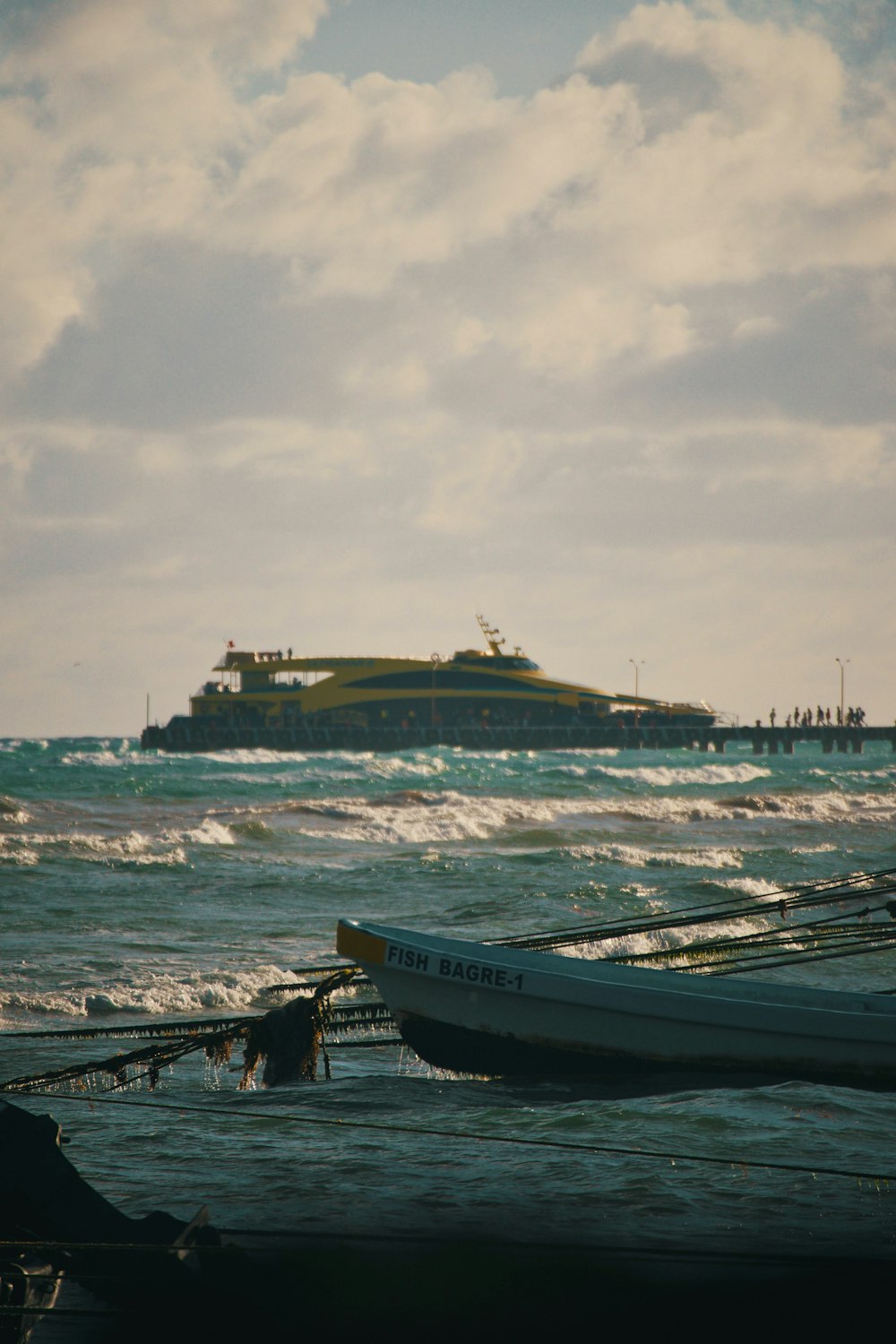 a boat in the ocean with a large cruise ship in the background