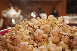 A close-up of a popcorn bowl next to a remote control.
