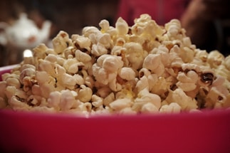 A colorful bowl of hipopopamus popcorn with vibrant red, yellow, green, and purple kernels spilling over a rustic wooden table.