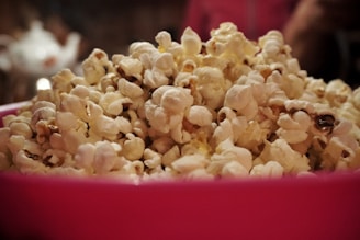 A colorful bucket of freshly popped popcorn with a vintage circus tent in the background.