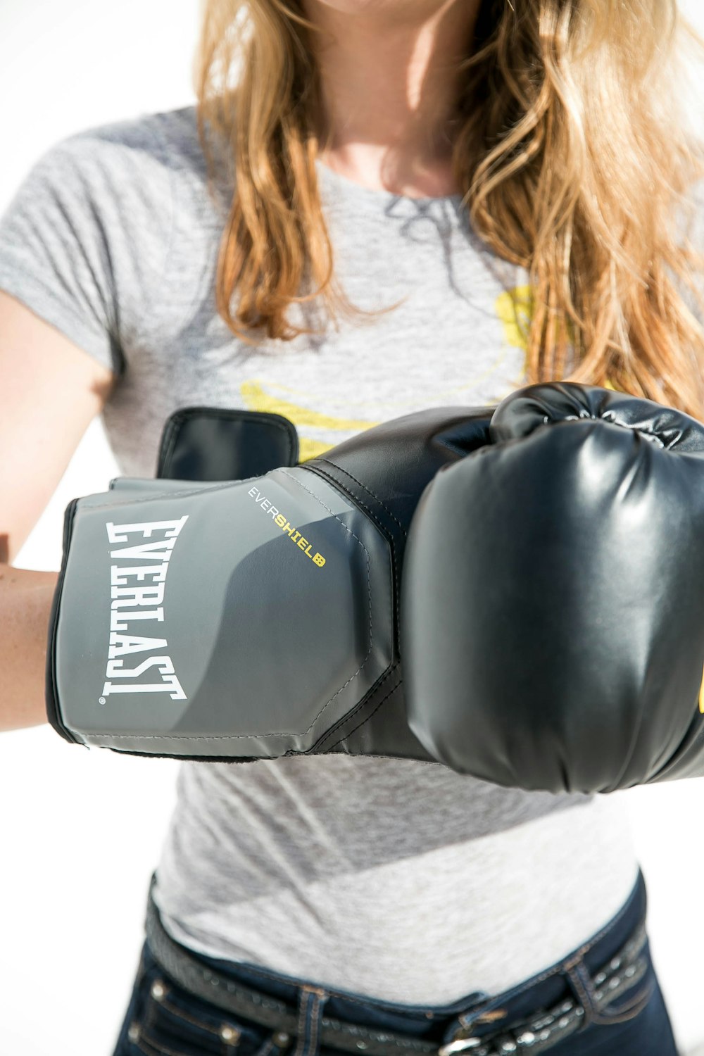 woman wearing gray with yellow crew-neck t-shirt and black Everlast boxing gloves standing