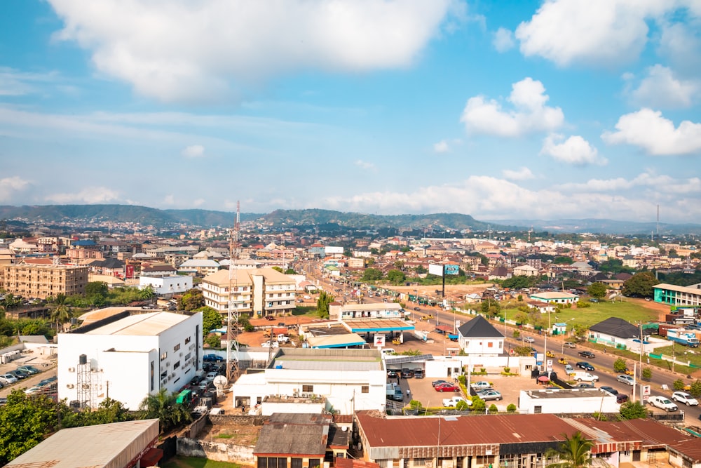 aerial photography of houses and buildings on green field viewing mountain under white and blue sky