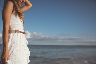 woman wearing white dress standing near the body of water