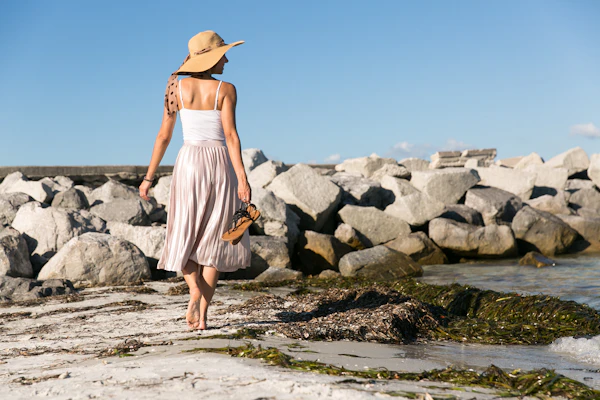 Woman in a sun hat walking by the sea