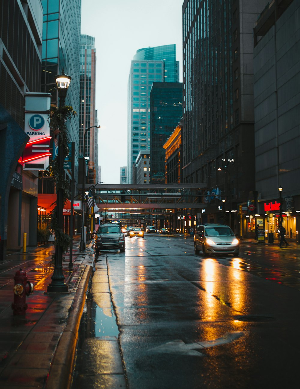 people walking on pathway near buildings and different vehicles on road during night time