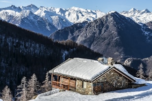 photography of brown house and snow-capped mountain during daytime