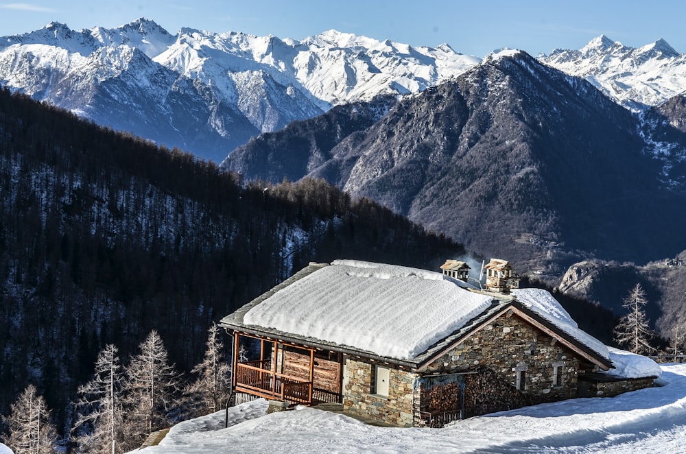 日中の茶色い家と雪をかぶった山の写真