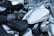 Several motorcycles are parked closely together. The focus is on a white motorcycle with chrome accents including the mirrors, engine parts, and instrument panel on the fuel tank. The seats are black and leather, and the motorcycles appear to be in good condition.