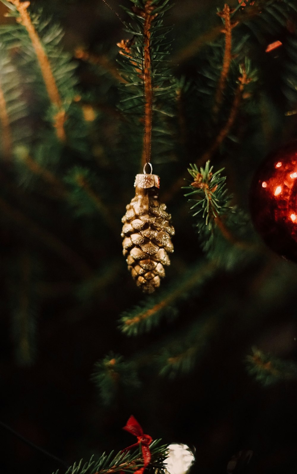 a pine cone ornament hanging from a christmas tree