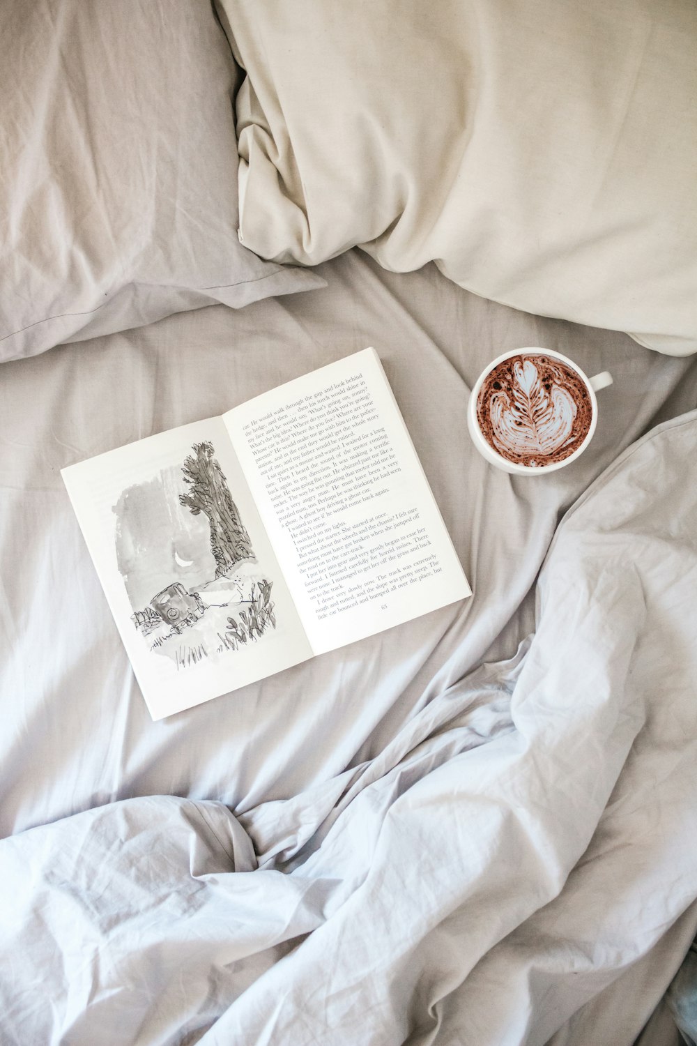 open book page near cappuccino and white pillows