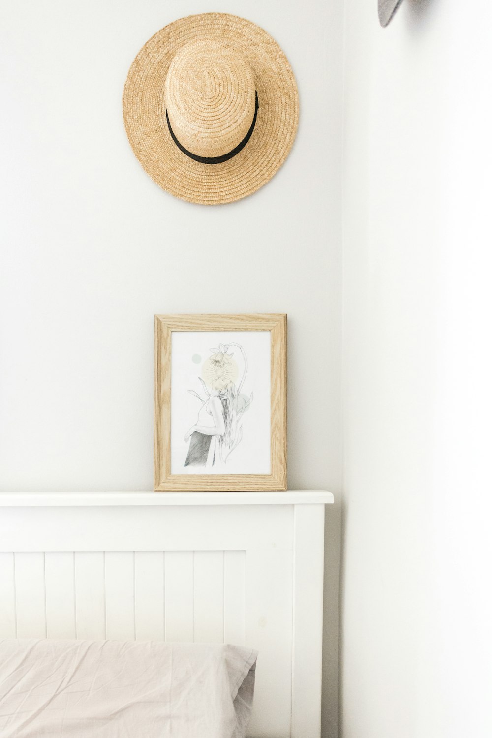beige sun hat near abstract painting with brown frame beside wall