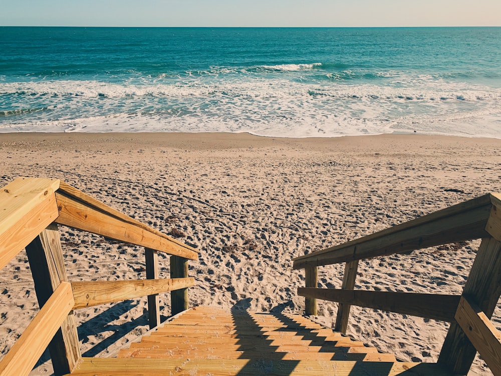 Escaliers en bois brun sur le sable du bord de mer pendant la journée