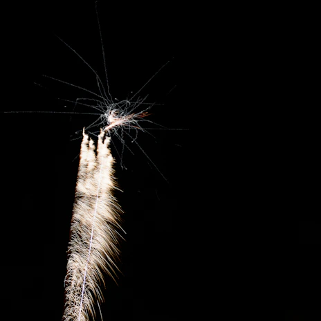 Close-up of a cold spark machine emitting bright, golden sparks against a dark stage background.