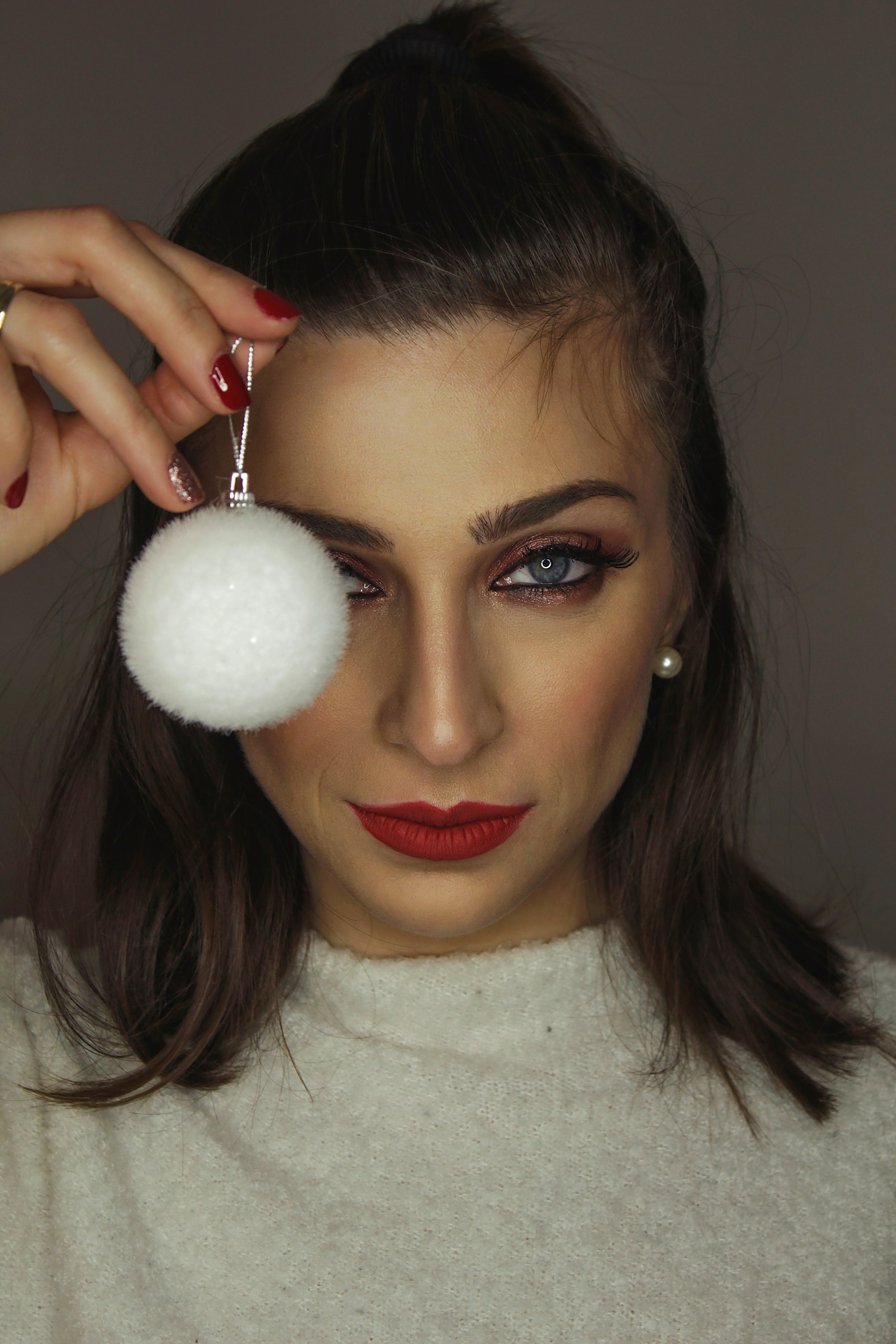 woman wearing white fur crew-neck top holding white fur bauble