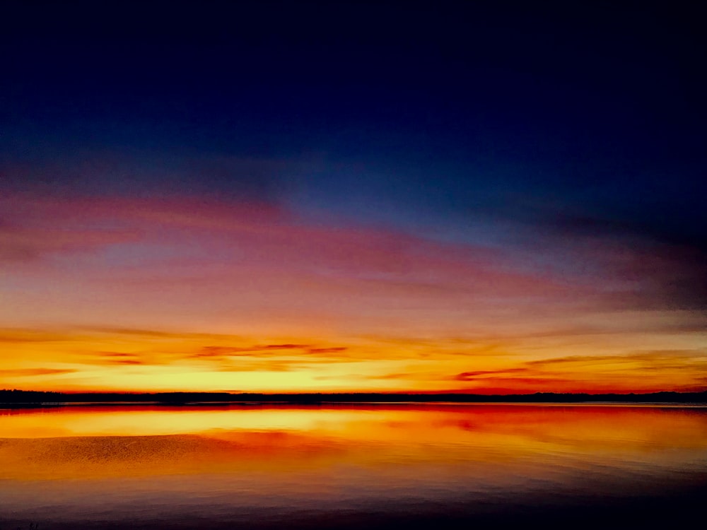 body of water under cloudy sky during golden hour