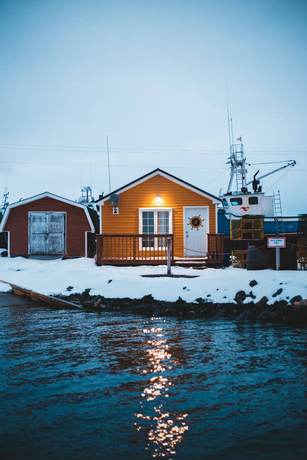 orange wooden house showing lighted outdoor lamp near body of water