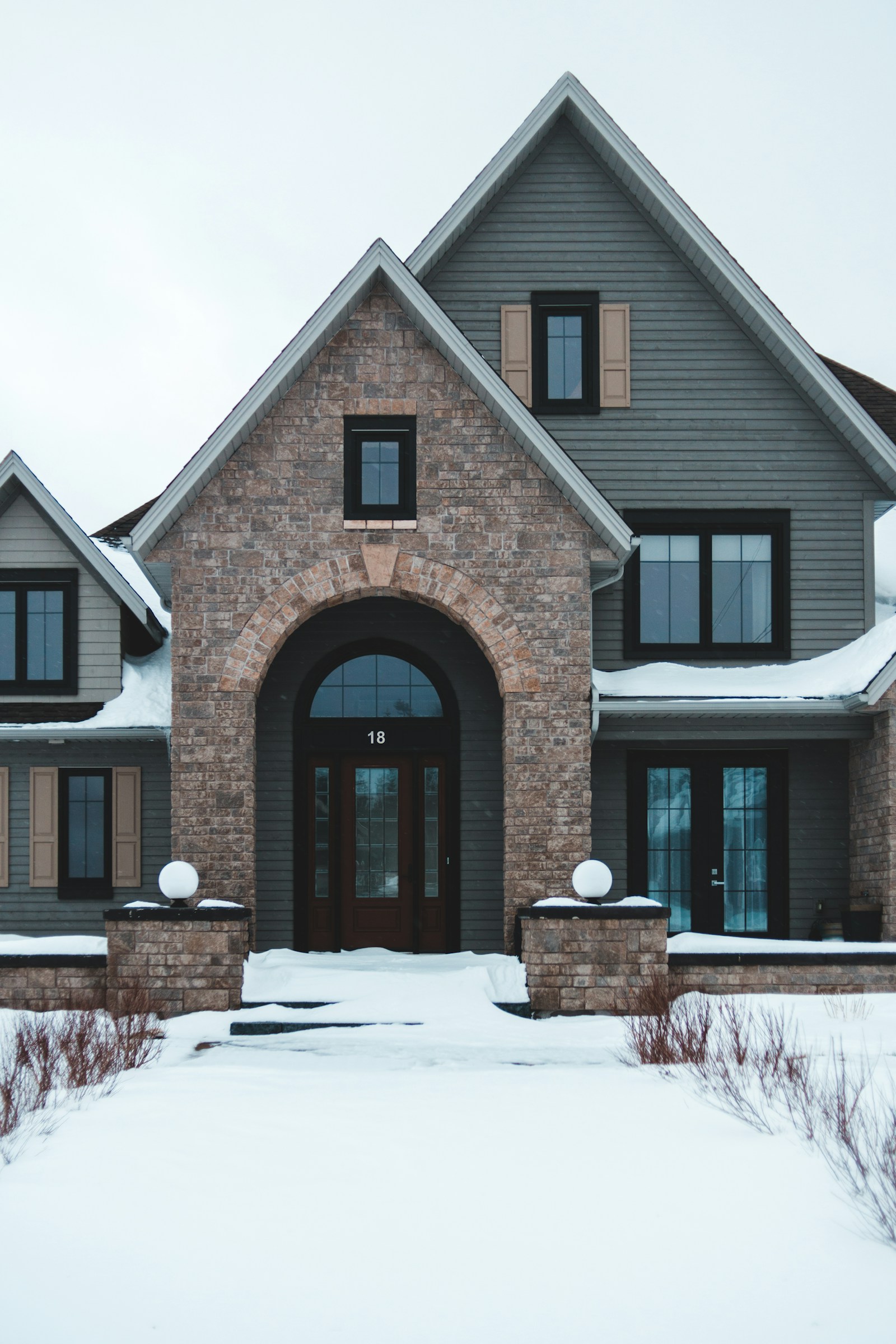 a newer two storey home with grand entrance on a snow-covered lot