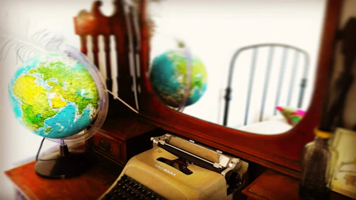 Elegant black and gold travel-themed desk with a vintage globe and a sleek laptop.