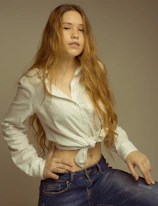 femme cheveux long en haut court blanc à manches longues et bas en jean bleu