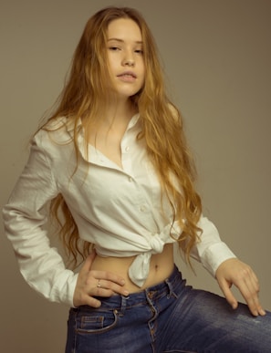 femme cheveux long en haut court blanc à manches longues et bas en jean bleu