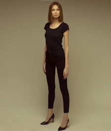 A confident Black woman standing tall in a soft beige outfit, radiating calm strength against a warm, minimalist background.