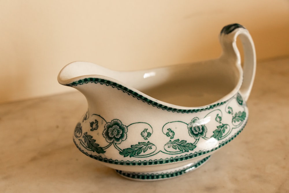 white and green ceramic sauce boat