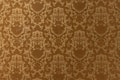 A vintage-style wallpaper with an intricate, repeating floral and damask pattern in shades of brown and beige. The design features ornate, symmetrical motifs that create a sense of elegance and classic decor.