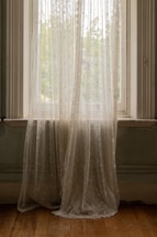 A cozy living room window dressed with soft sheer curtains and elegant curtain rods.