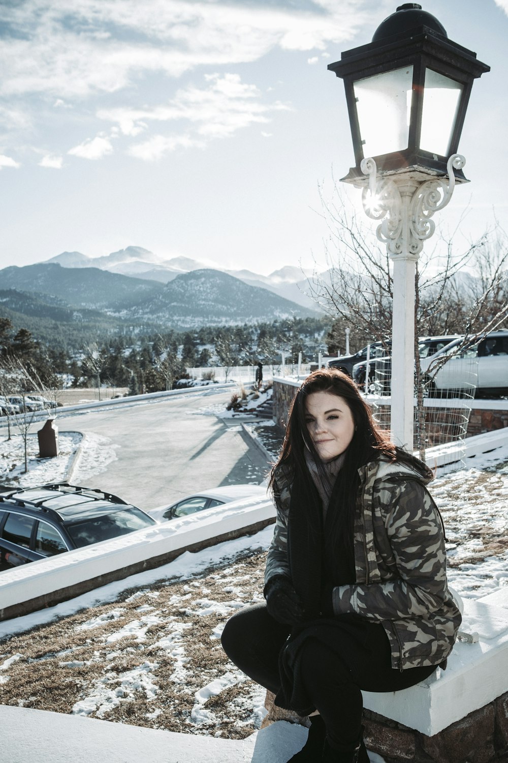 woman in gray camouflage jacket and black pants sitting outdoors