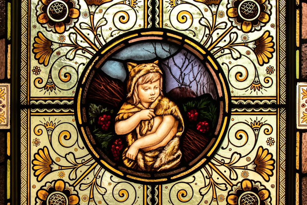 a stained glass window with a woman holding a cat