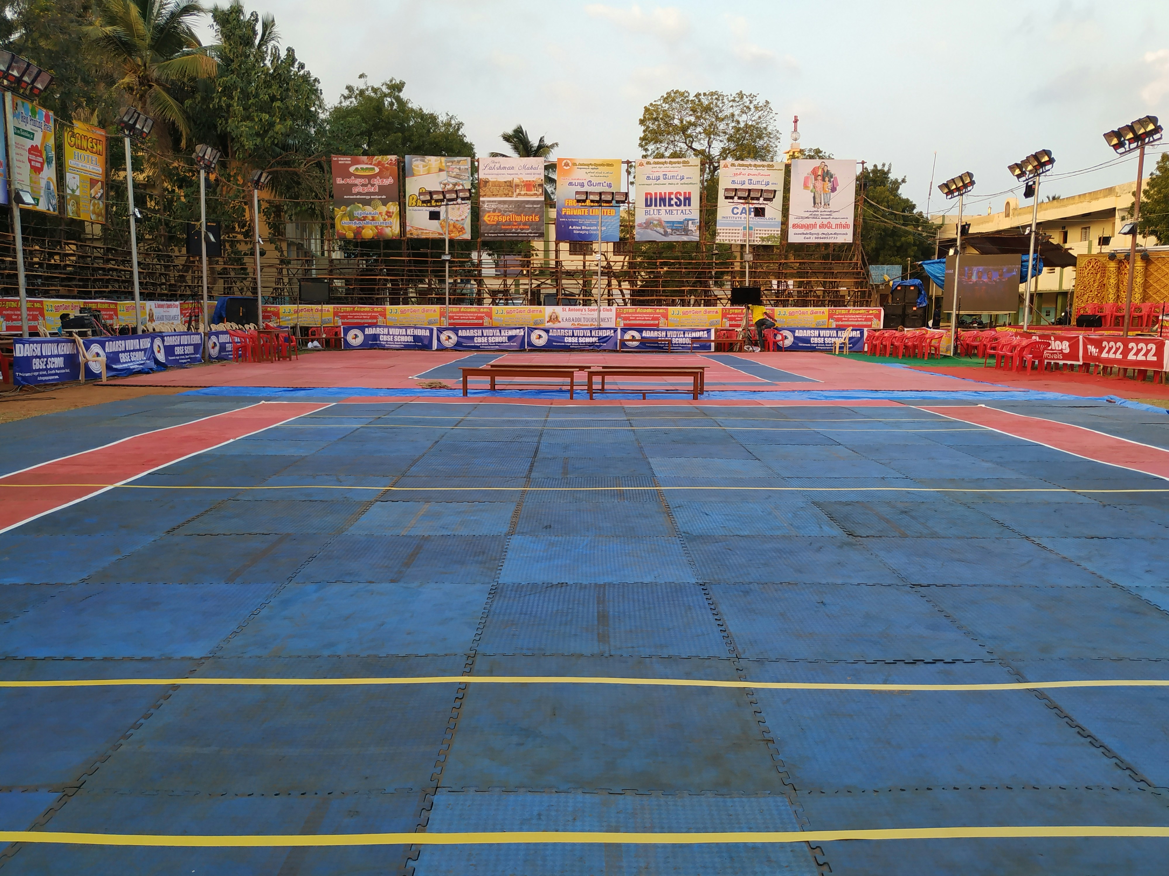 Kabaddi raider mid-tackle on a brightly lit mat with intense crowd energy