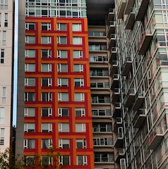 Elegant urban apartment building with bold red accents matching the brand colors.