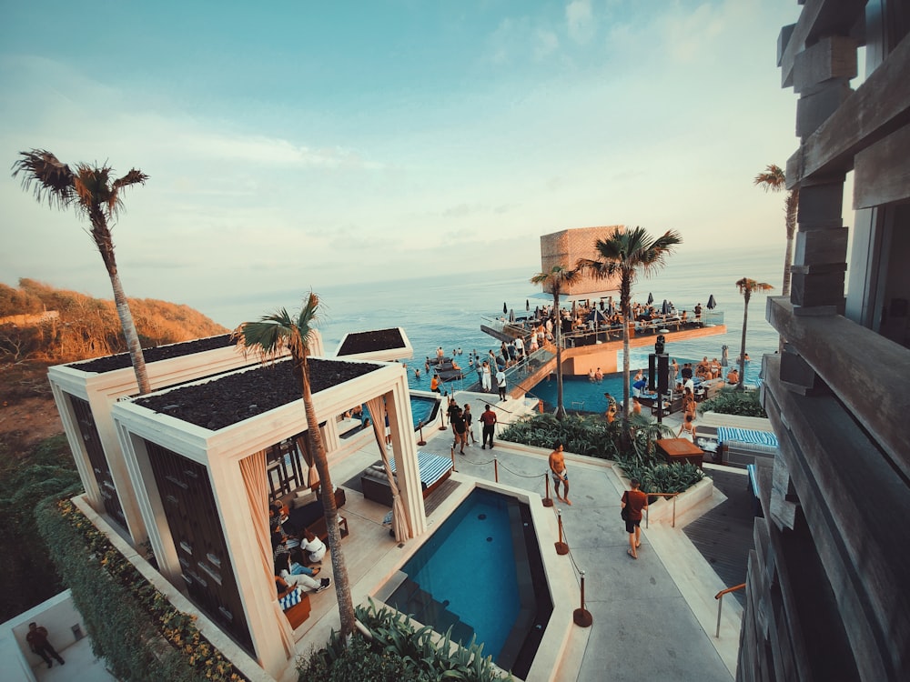 a group of people standing around a pool next to the ocean