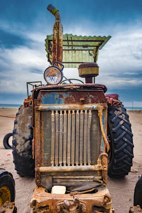 A close-up of a tractor undergoing mechanical maintenance in a rural farm setting