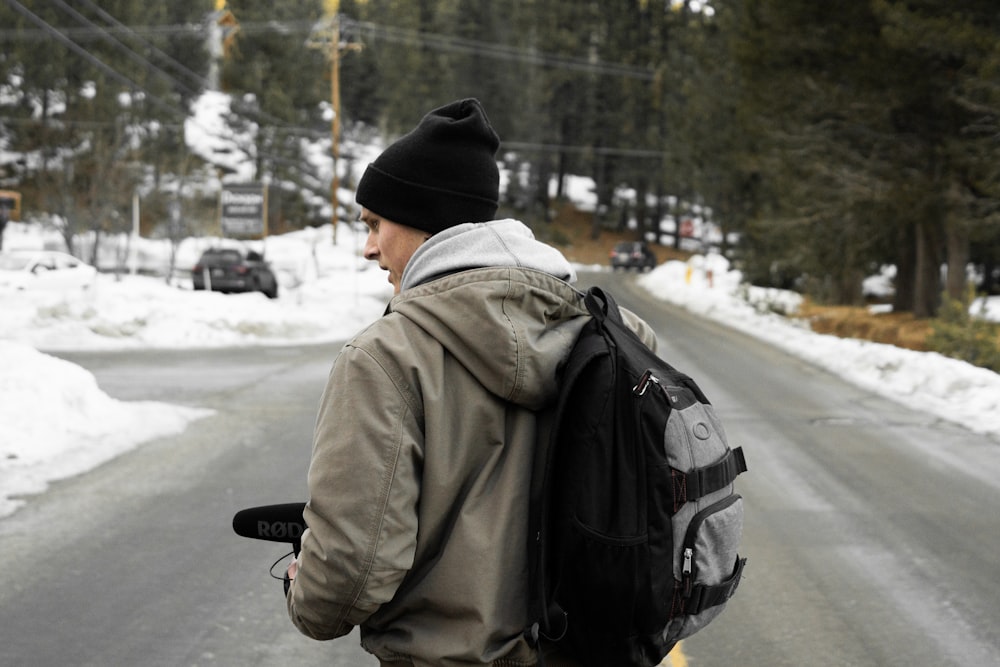 man wearing gray jacket and black backpack